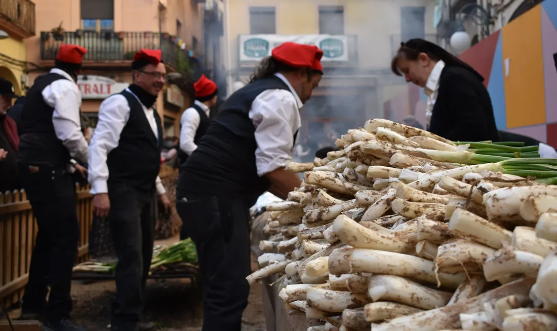 Pagesos coent calçots a la Festa del Calçot de Valls, per explicar les calçotades de restaurants.