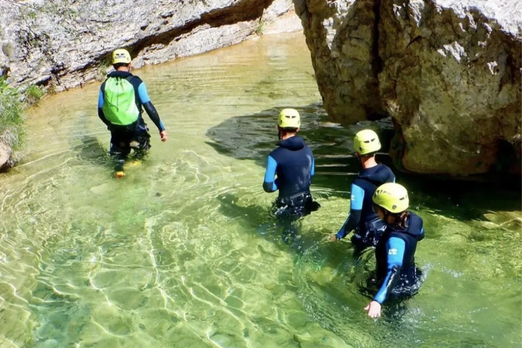 Grupo de participantes practicando barranquismo en una poza de aguas transparentesGrupo de espeleología e