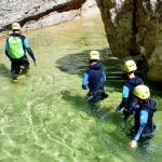 Grupo de participantes practicando barranquismo en una poza de aguas transparentesGrupo de espeleología e